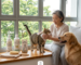 Indoor cat grooming in a Singapore HDB apartment, showing a pet owner using gentle pet wipes on a tabby cat next to a bottle of neutral cat grooming shampoo, a grooming brush, and a Golden Retriever.